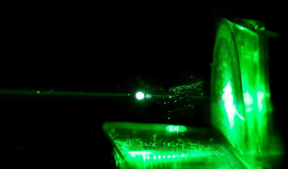 Haz láser verde atravesando una muestra durante la caracterización de dispositivos de plasma