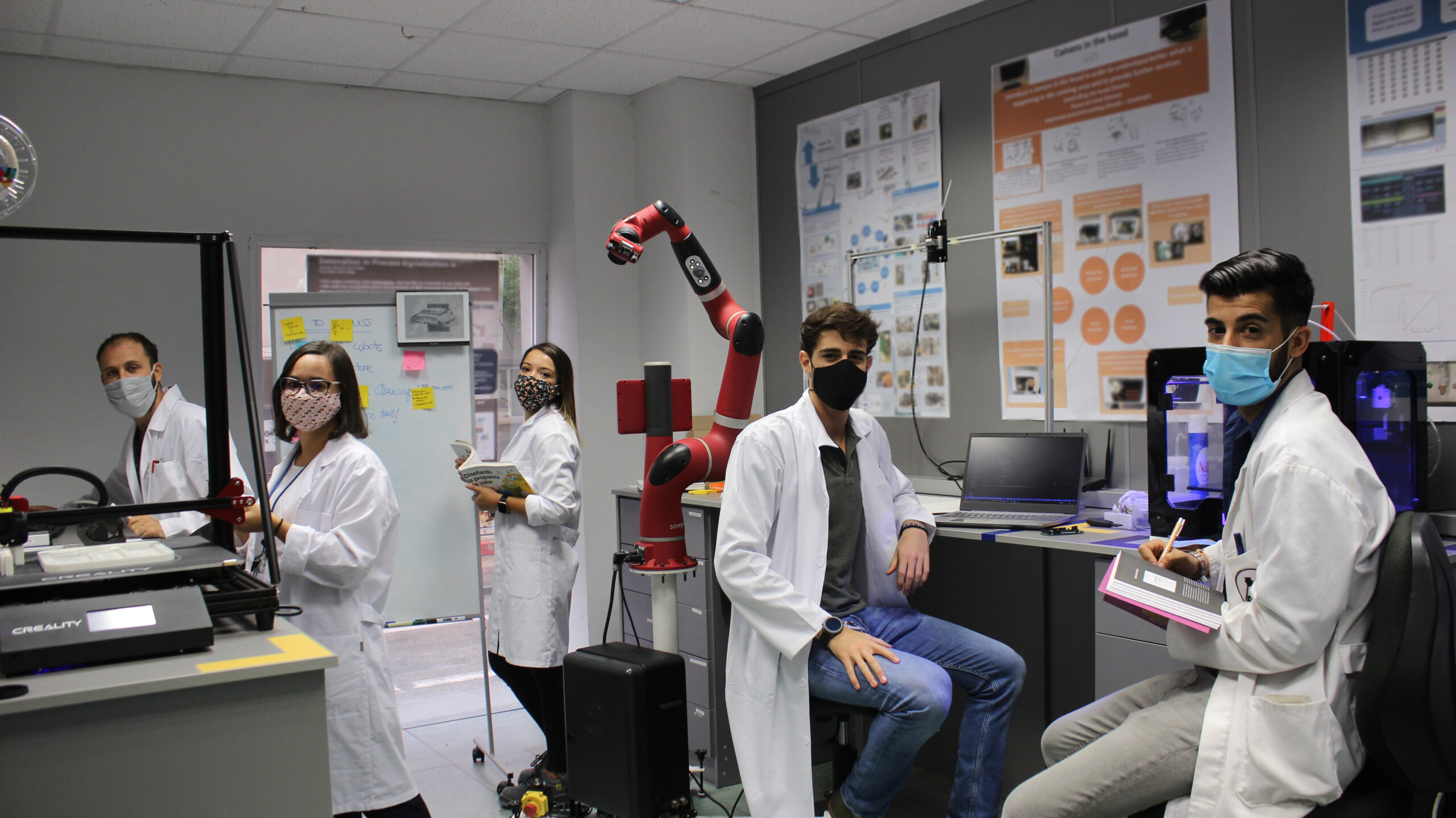 Equipo de INFINITIA junto al brazo robótico y las impresoras 3D del área de prototipado