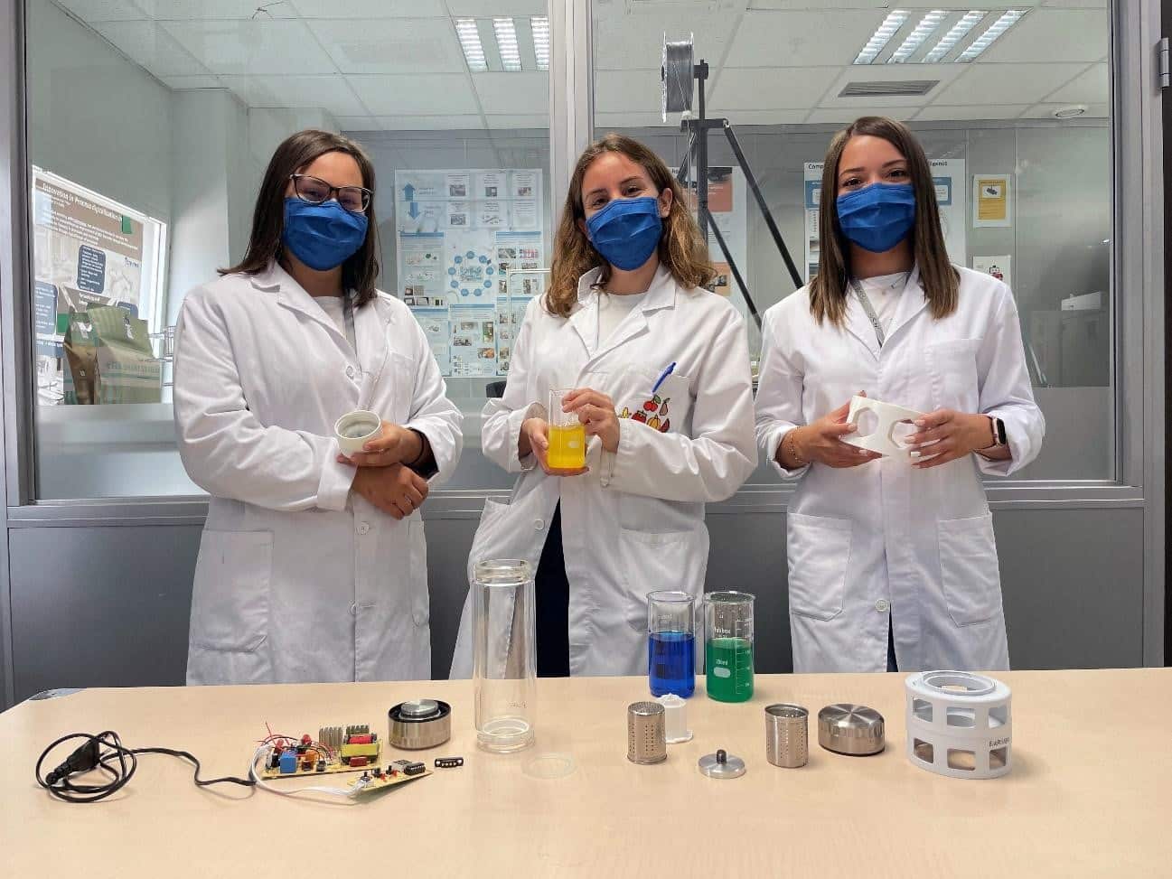 Product design and flavored waters from an interdisciplinary approach Tres técnicos de laboratorio evaluando muestras de producto y envases sobre la mesa de trabajo