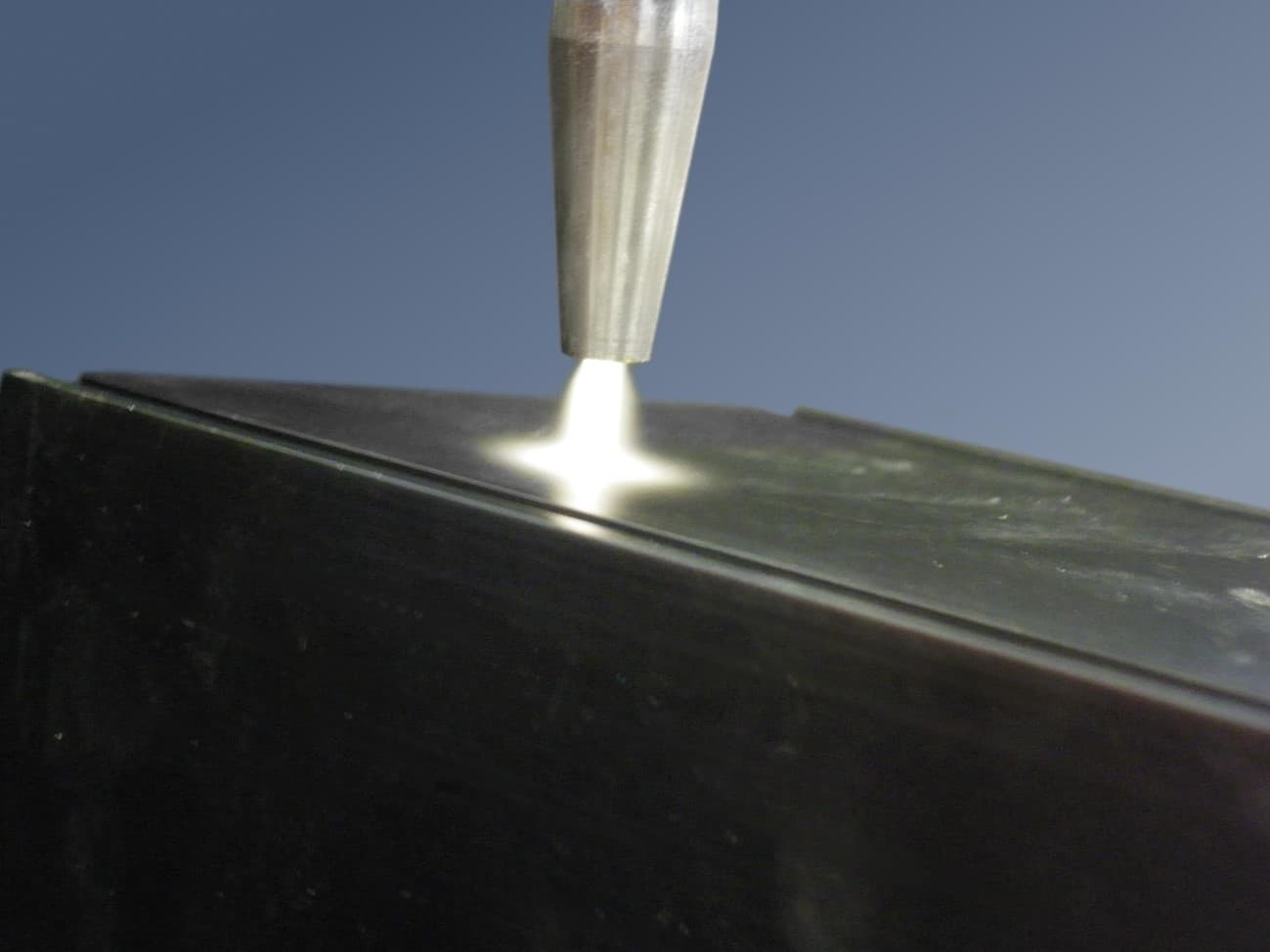 Boquilla aplicando tratamiento de plasma sobre la superficie de un material