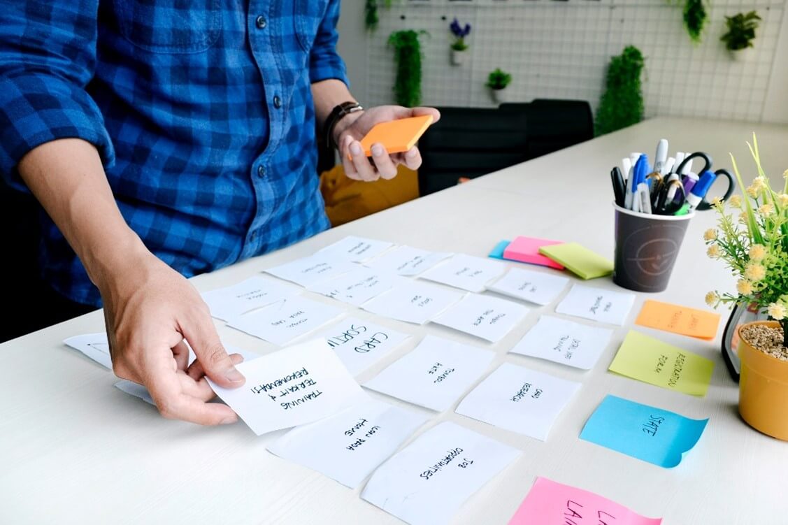 Sesión de trabajo ordenando tarjetas sobre una mesa durante un proceso de design thinking con el método de doble diamante