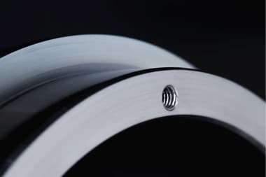 Detalle de una superficie metálica curva con recubrimiento protector, en el estudio de recubrimientos sostenibles resistentes a la corrosión