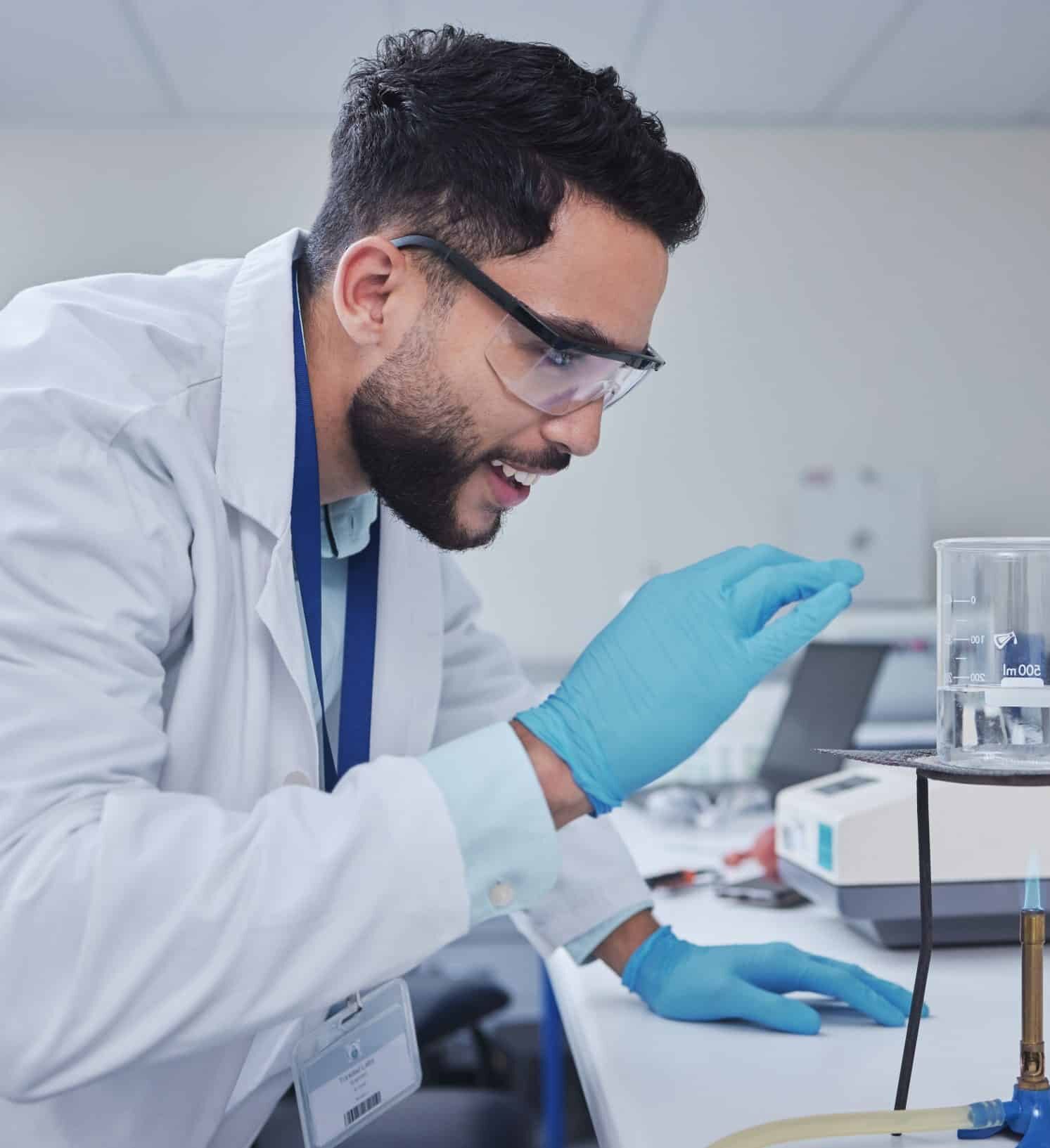 Ensayos de emisiones Técnico de laboratorio manipulando una muestra con guantes y gafas de protección