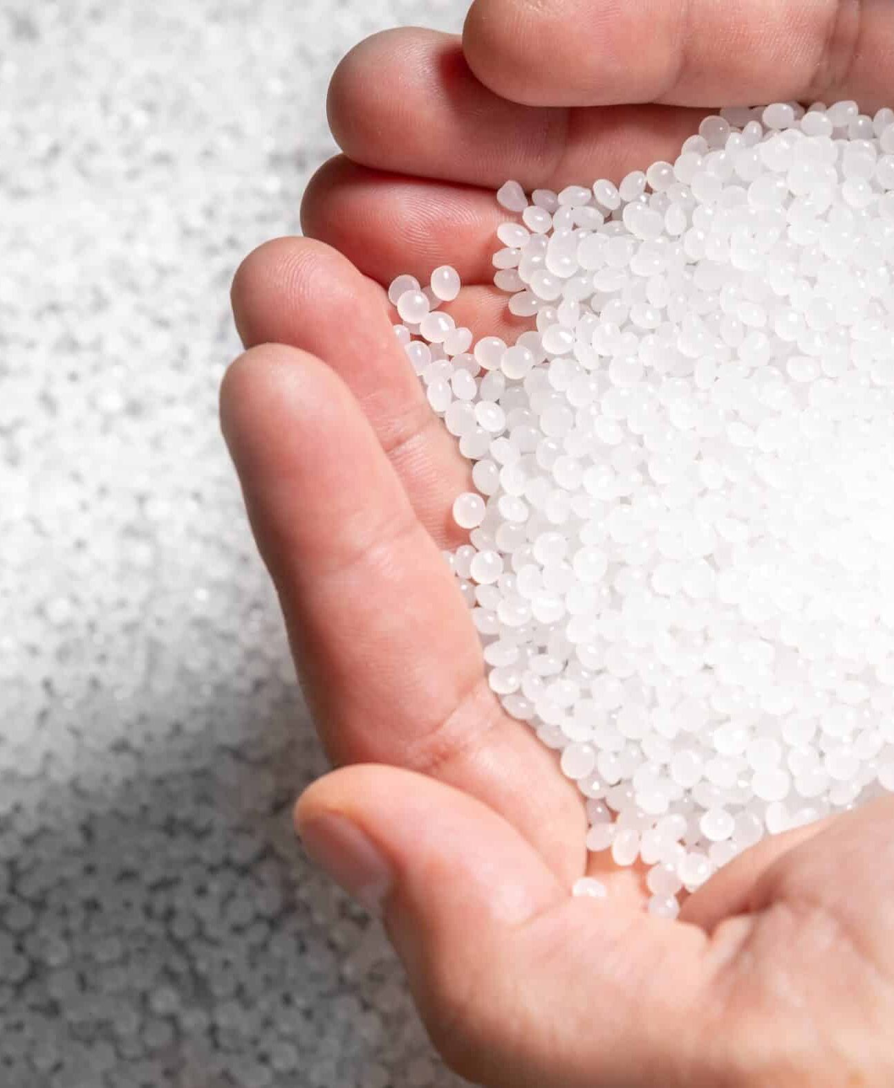 Manos sosteniendo granza de plástico reciclado antes de su análisis de impurezas y contaminantes