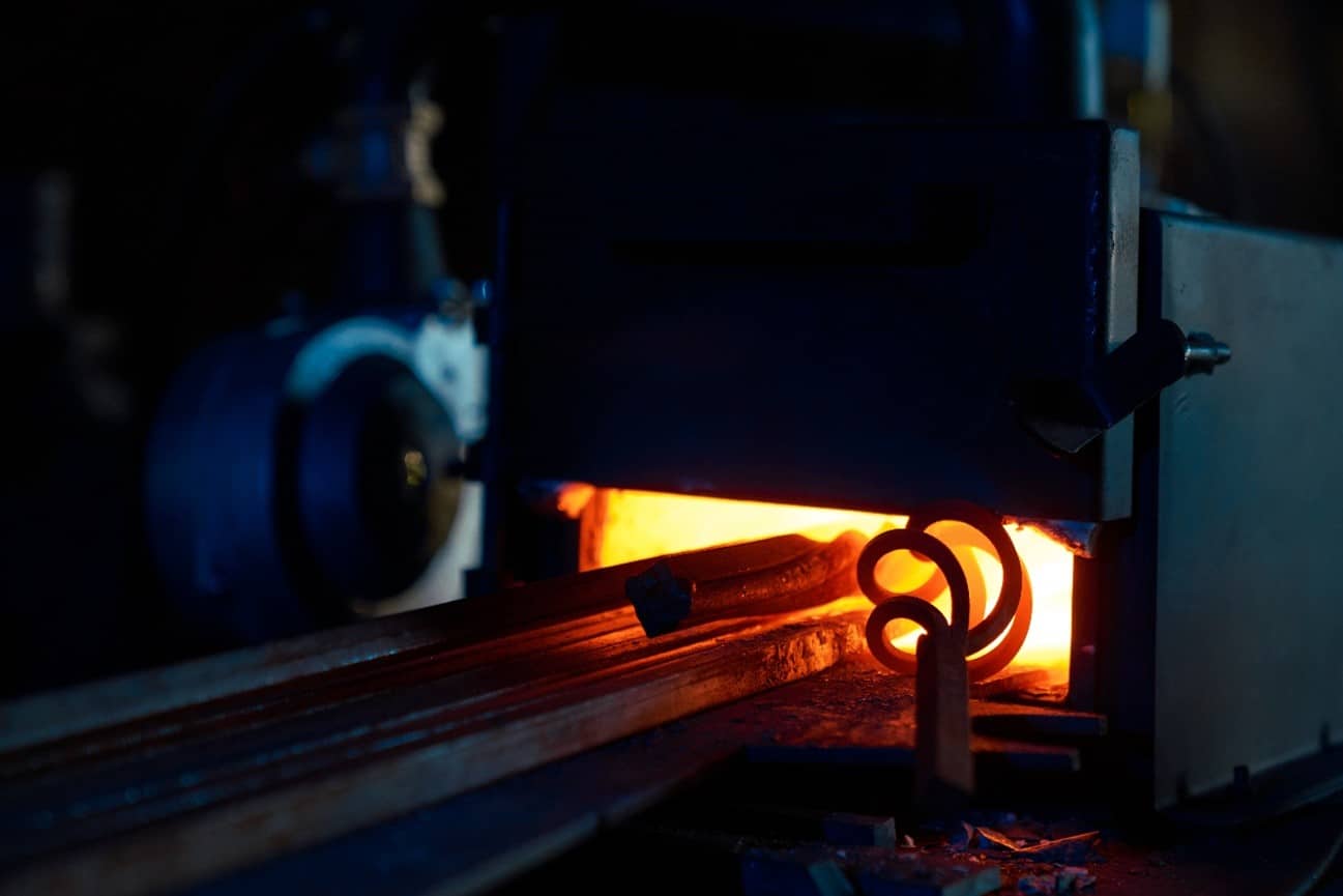 Análisis de tratamientos térmicos de metales Pieza metálica incandescente saliendo de un horno industrial durante un tratamiento térmico