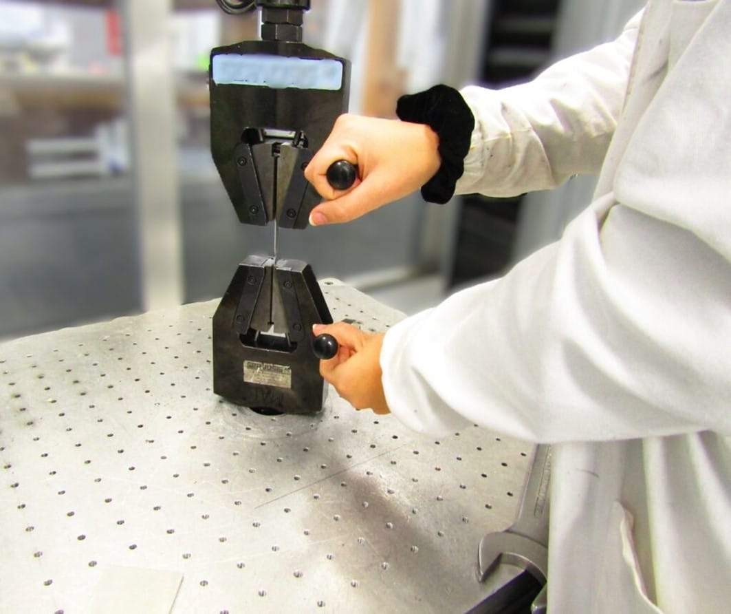Análisis de tratamientos térmicos de metales Técnico manipulando con guantes una probeta metálica preparada para su análisis metalográfico