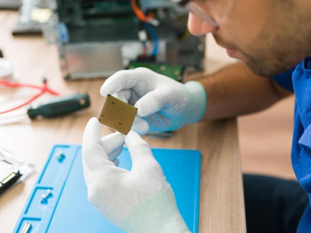 Technician analyzing a microchip to detect aesthetic defects in electronic components in a laboratory