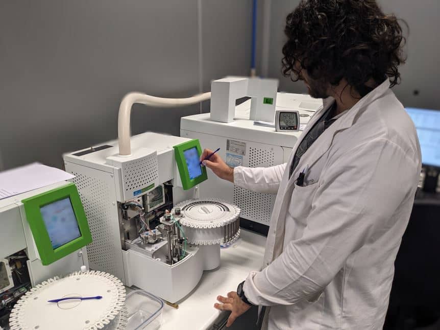 Laboratory technician operating gas chromatography equipment for chemical analysis of gases generated at high temperature in steel