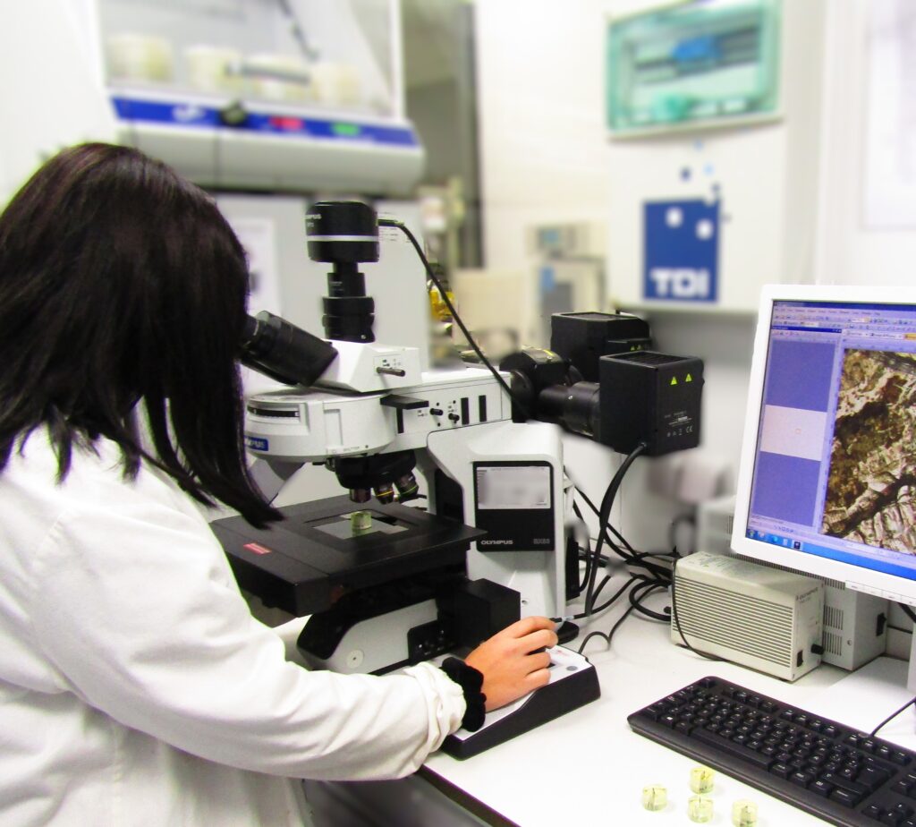 Técnica observando grietas por fatiga en material mediante microscopio en laboratorio