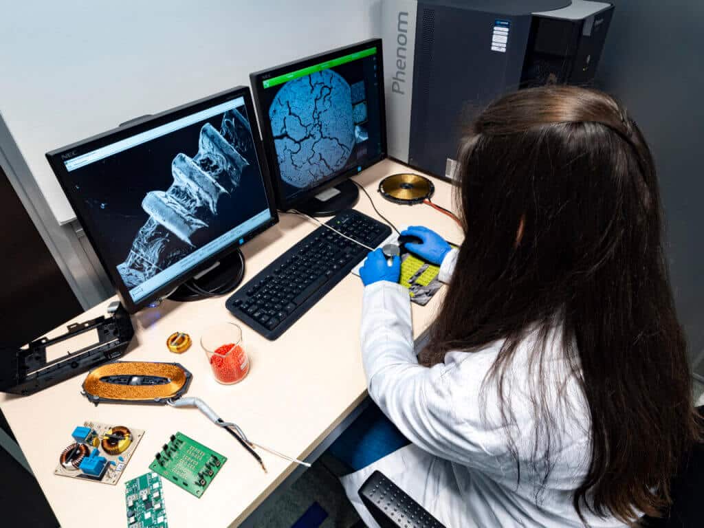 Ingeniera analizando microestructura de material en microscopio electrónico durante un análisis de fallo en materiales