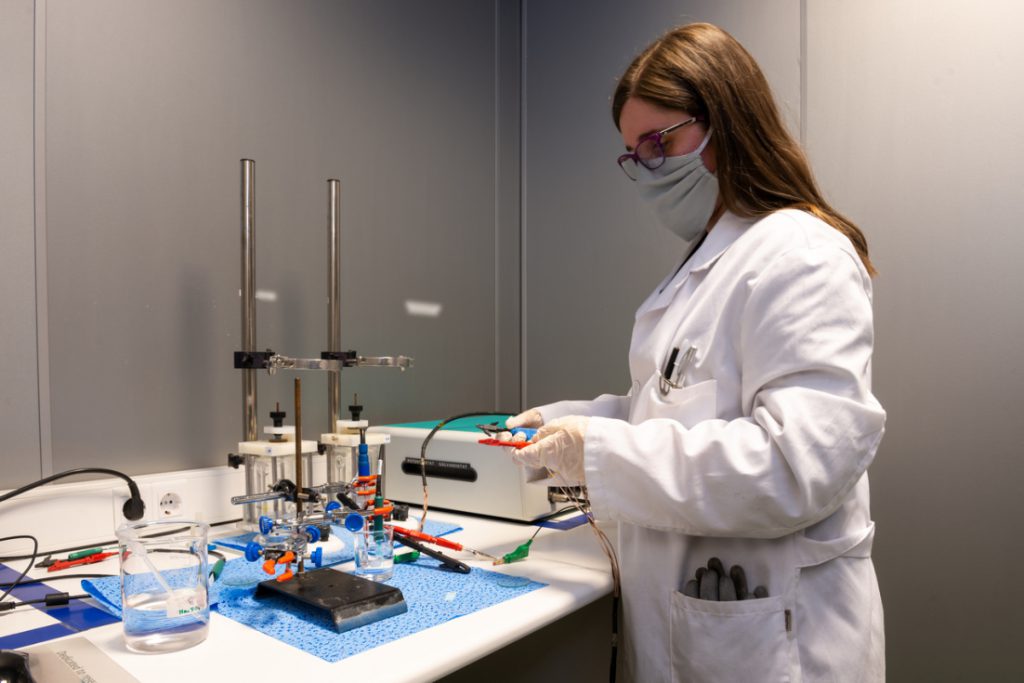 Técnico realizando ensayos electroquímicos de corrosión en materiales metálicos con equipamiento de laboratorio