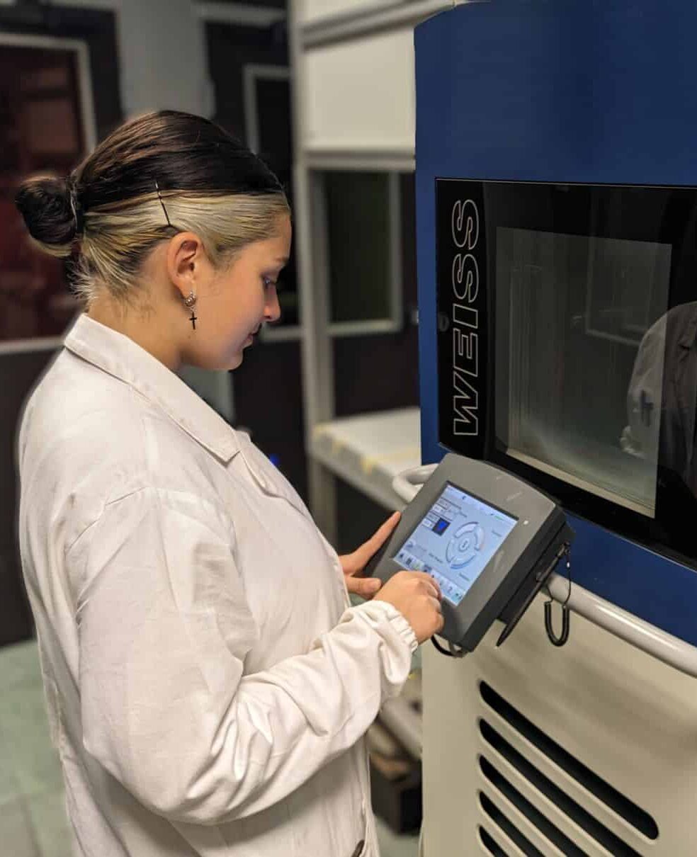 Technician performing laboratory testing in climatic chamber to evaluate industrial materials