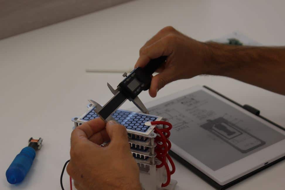 Técnico de Infinitia midiendo cota crítica con calibre digital sobre prototipo de dispositivo electrónico durante fase de validación