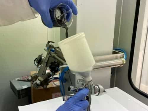 Mejora de procesos de esmaltado mediante calentamiento por inducción Operario aplicando esmalte con pistola en una cabina de recubrimiento