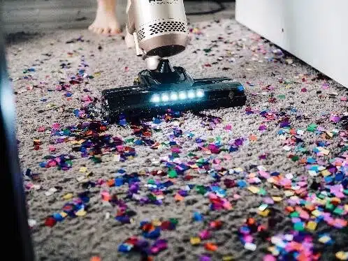 Cordless vacuum cleaner picking up confetti from a carpet
