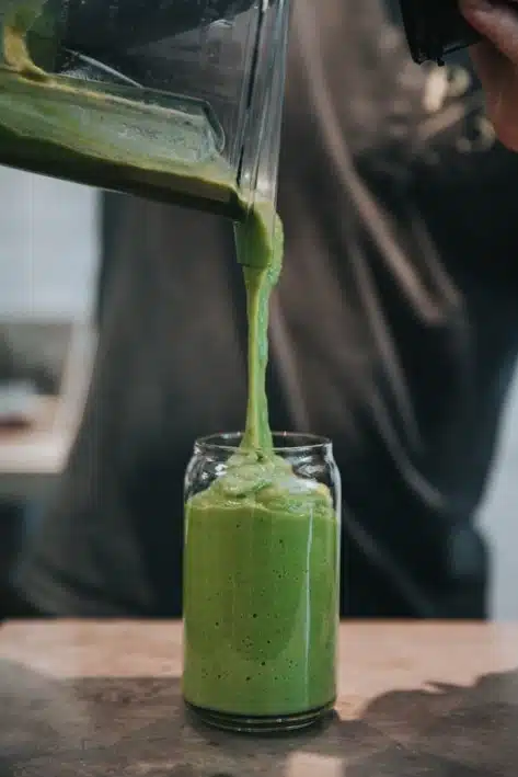 Green smoothie poured into a glass, an example of processed food