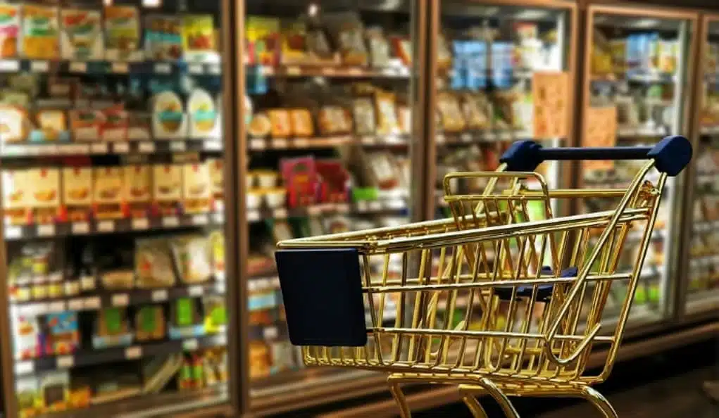 Shopping trolley in a supermarket aisle with food products