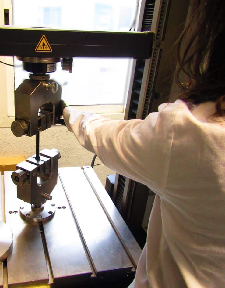 Técnico realizando un ensayo mecánico sobre una probeta de material compuesto en la máquina de ensayos
