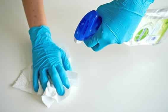 Diseño conceptual de nuevos productos para limpieza de superficies en el hogar Manos enguantadas limpiando una superficie con bayeta y producto, contexto del diseño conceptual de productos de limpieza del hogar