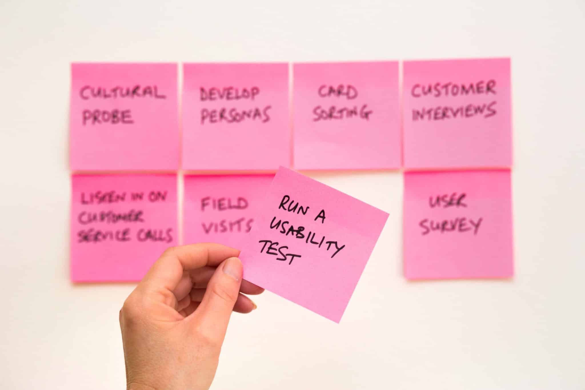 Hand holding sticky notes from a user research session