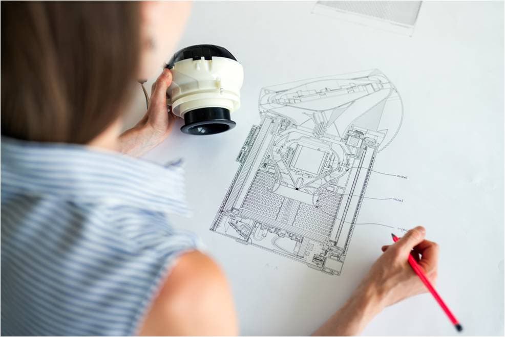 Component design by reverse engineering and 3D scanning Technician examining a part with a magnifier over its technical drawing in a reverse engineering process