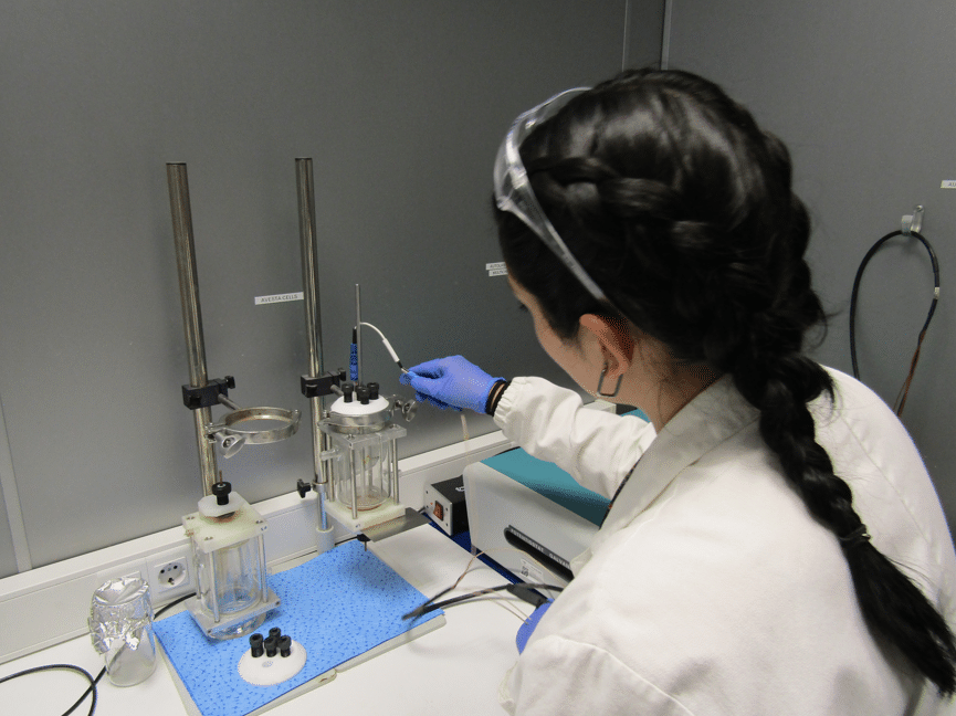 Técnica de laboratorio preparando una celda de ensayo en el banco durante la homologación de un material