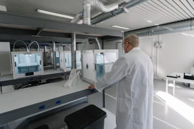 3D printing to detect design flaws in leak-tight parts Technician in a lab coat working next to a row of 3D printers in the laboratory