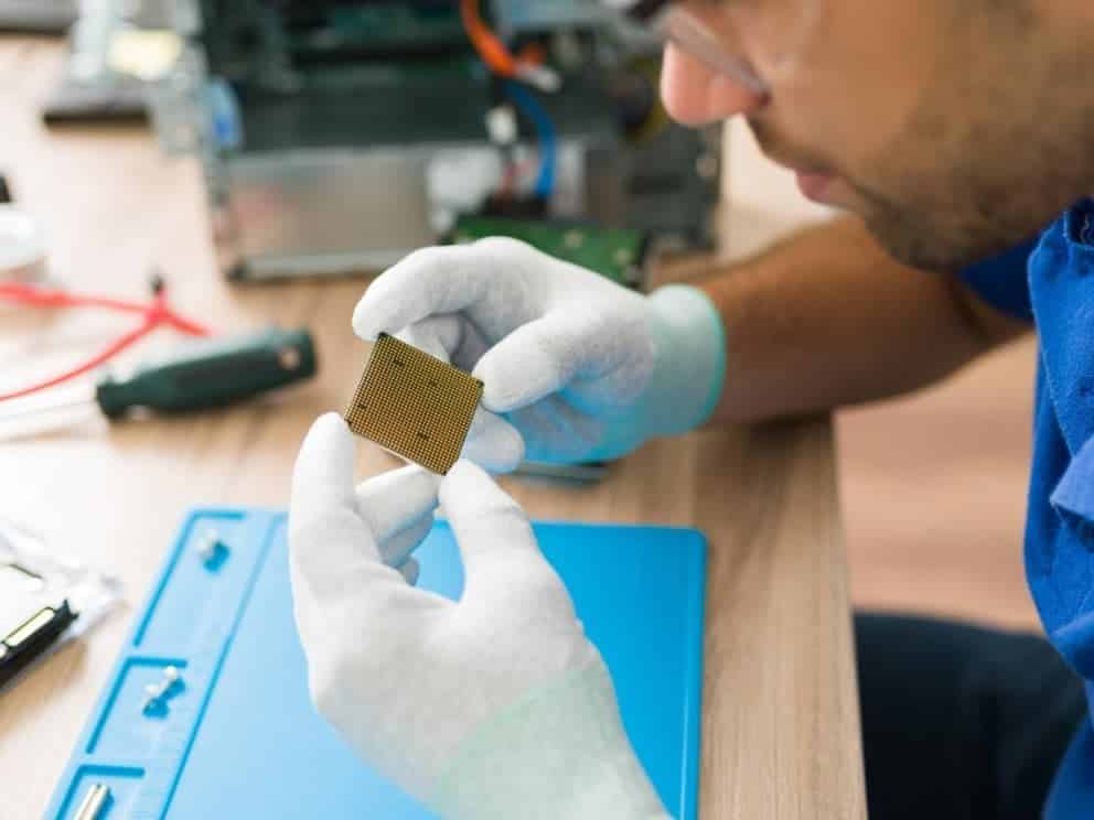 Análisis de defectos estéticos en componentes electrónicos para mejorar la calidad del producto Técnico con guantes manipulando un componente electrónico en el banco de trabajo